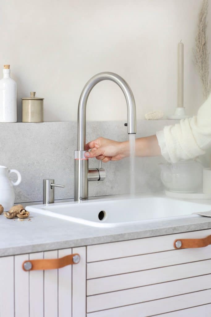 Frau bedient Quooker Wasserhahn aus Edelstahl