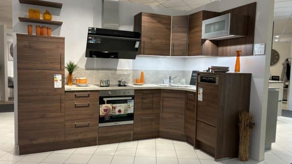 kleine Küchenzeile mit silbernen Griffen in dunklerem Holz mit heller Arbeitsplatte und erhöhter Spülmaschine